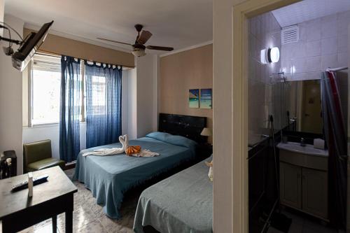 a bedroom with two beds and a bathroom with a sink at Hotel Vial Center in Mar del Plata