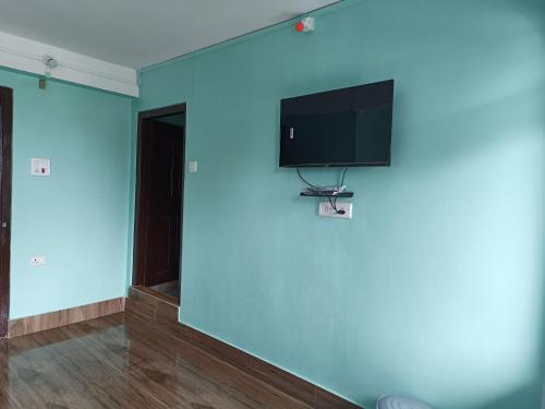 Habitación con pared azul, TV y canasta de baloncesto. en Hotel PineWood Tawang, en Tawang