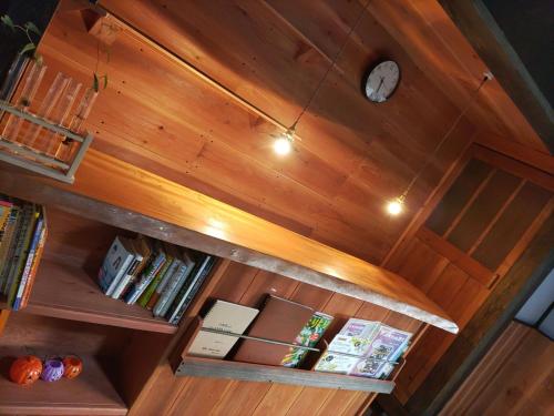 um relógio no topo de uma estante de livros com livros em もりのもむ Morinomomu Guest House in Mitsuo 