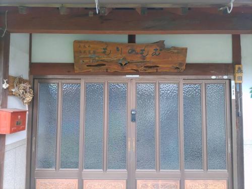 uma porta da frente de um edifício com um sinal por cima em もりのもむ Morinomomu Guest House in Mitsuo 
