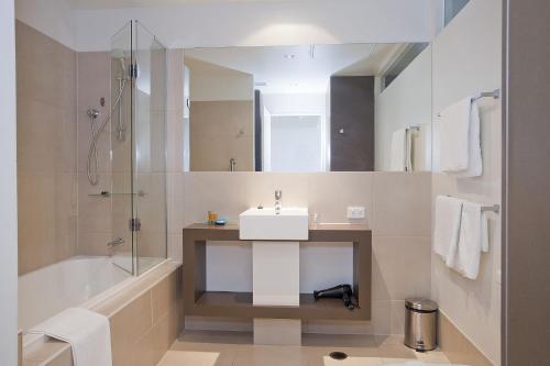 een badkamer met een wastafel, een bad en een douche bij Resort Apartment 263 in Torquay