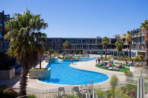 a pool at a resort with palm trees and a building at Resort Penthouse 301 in Torquay