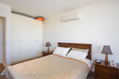 1 dormitorio con 1 cama, 2 mesitas de noche y 2 lámparas en Resort Penthouse 301, en Torquay
