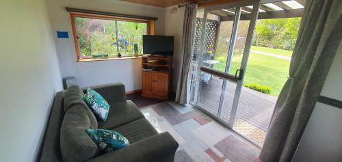 a living room with a couch and a sliding glass door at Golden Bay Holiday Park in Onekaka