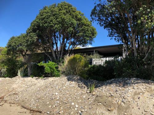 a house sitting on top of a hill with trees at Golden Bay Holiday Park in Onekaka