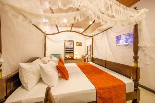 a bedroom with a canopy bed with orange and white pillows at Mimoza Mirissa in Mirissa