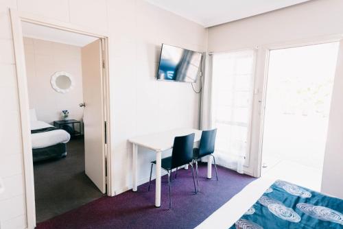 Habitación con mesa, sillas y cama en Motel Poinsettia, en Port Augusta