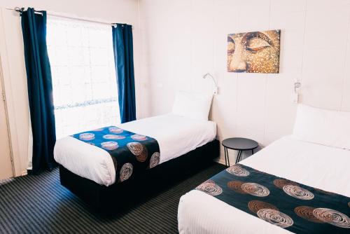 a hotel room with two beds and a window at Motel Poinsettia in Port Augusta