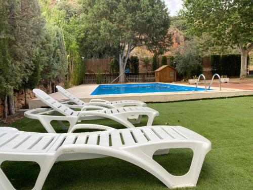 um grupo de espreguiçadeiras brancas ao lado de uma piscina em Villa Emilia 2 em Ossa de Montiel