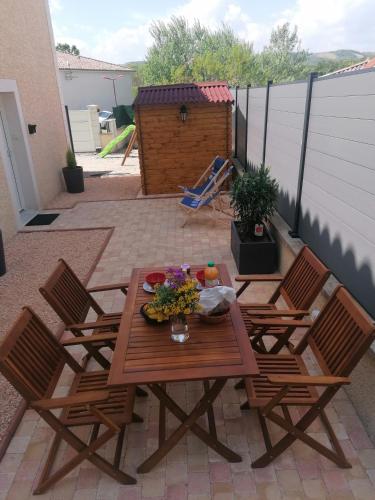 a patio with a table and chairs with flowers on it at Charmant appartement T2 dans villa avec en supplément spa extérieur de mai à septembre in Laveyron