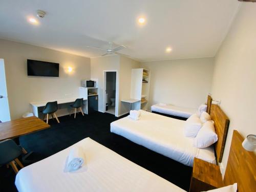 a hotel room with two beds and a desk at Nowra Motor Inn in Nowra