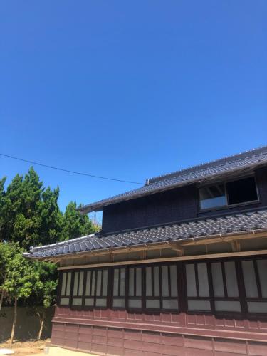 a building with a roof and trees in the background at 島宿糸 in Iki