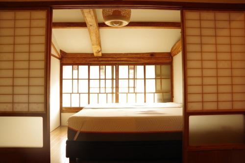 1 dormitorio con 1 cama en una habitación con ventana en 島宿糸, en Iki