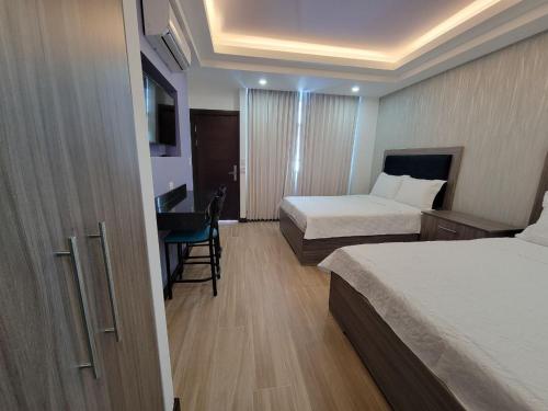 プンタレナスにあるHotel Cayugaのベッド2台とデスクが備わるホテルルームです。