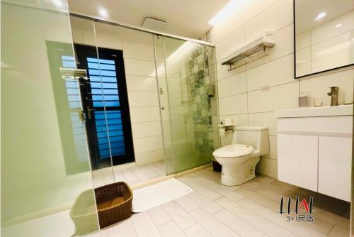 a bathroom with a toilet and a glass shower at Three Adds One Homestay in Luodong