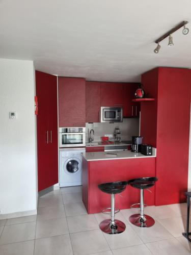 a kitchen with red cabinets and a washing machine at Hikoa Hendaia-Hendaye plage in Hendaye