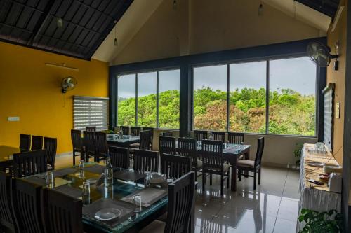 Un comedor con mesas y sillas y grandes ventanales. en Pine Clough Resort Vagamon, en Vagamon