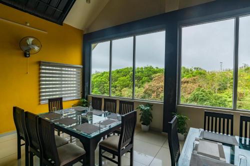 Un comedor con mesa y sillas y ventanas. en Pine Clough Resort Vagamon, en Vagamon