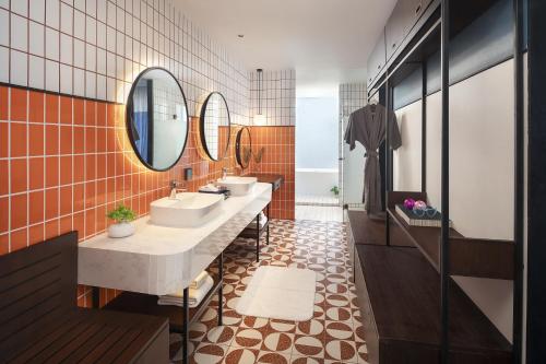a bathroom with two sinks and two mirrors at Avani Chaweng Samui Hotel & Beach Club in Chaweng