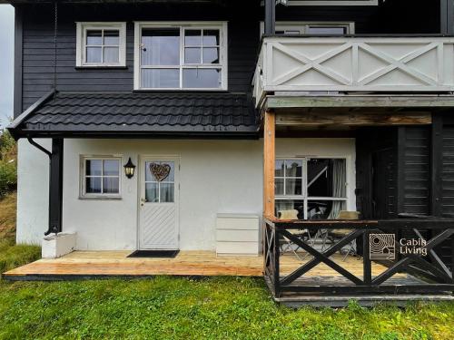 a house with a porch and a wooden deck at Nice apartment with Sauna and ski in out Trysil in Trysil