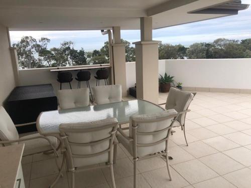 a glass table and chairs on a patio at Grand Mercure Allegra Hervey Bay in Hervey Bay