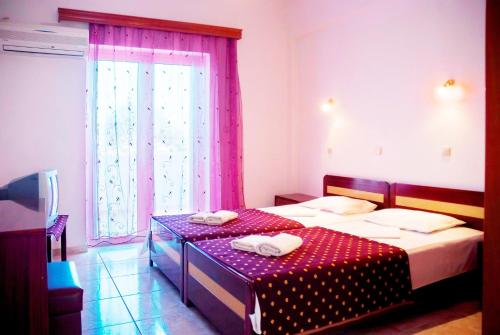a bedroom with two beds and a window with pink curtains at Villa Agnanti Boutique in Grammatiko
