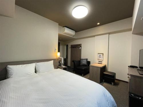 a hotel room with a large bed and a chair at Hotel Route-Inn Saku Minami Inter in Saku