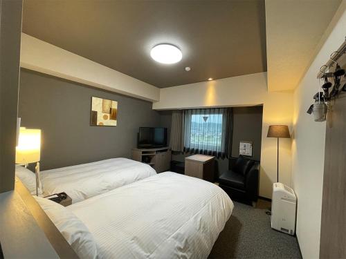 a hotel room with two beds and a television at Hotel Route-Inn Saku Minami Inter in Saku