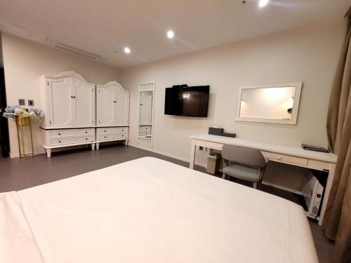 a bedroom with a bed and a desk and a tv at Embledon Hotel in Ansan