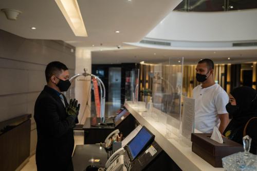 two men wearing face masks standing in a store at Grandia Hotel in Bandung