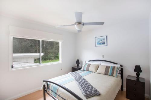 a bedroom with a bed and a ceiling fan at Beach Retreat in Mollymook