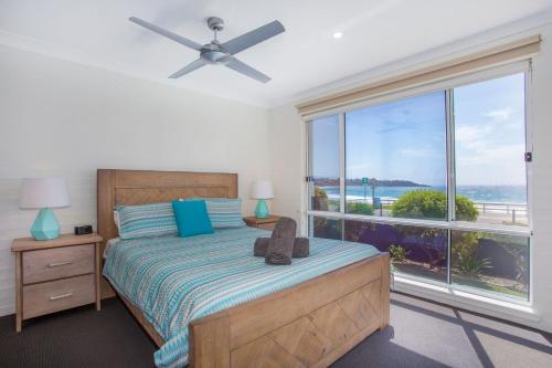 a bedroom with a bed and a large window at Mariners 2 in Mollymook