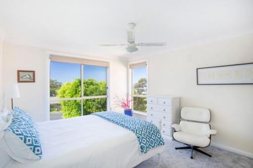 a bedroom with a bed and a chair and a window at Summer Days in Mollymook