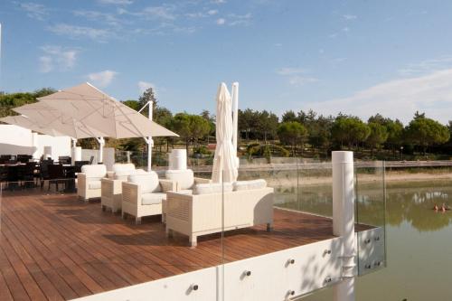 a deck with white chairs and an umbrella and water at Villaggio La Pescaccia in San Clemente