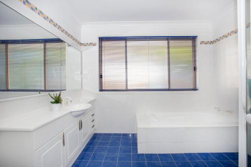 a white bathroom with a sink and a tub at Leafy Retreat in Ulladulla