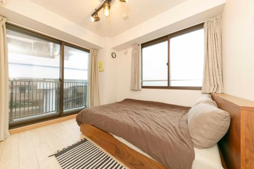 sypialnia z łóżkiem i dużymi oknami w obiekcie Gamadas BLD w Tokio