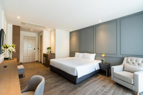 een hotelkamer met een bed en een stoel bij One Patio Hotel Pattaya - SHA Extra Plus in Pattaya