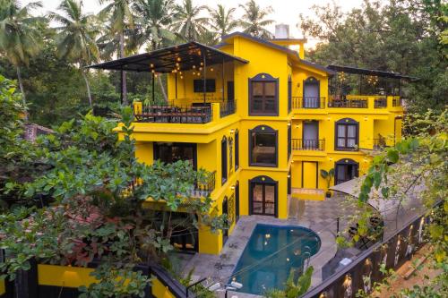 a yellow house with a pool in front of it at Whoopers Boutique Hotel, Anjuna in Anjuna