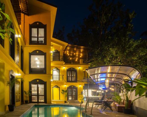 a house with a swimming pool in front of a building at Whoopers Boutique Hotel, Anjuna in Anjuna