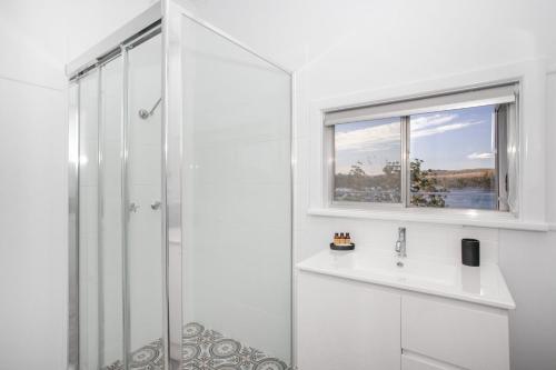 a white bathroom with a shower and a sink at Home On the Water in Yatte Yattah