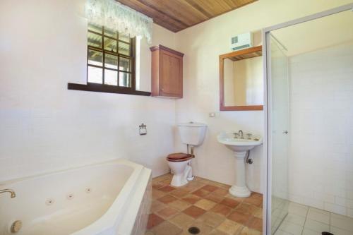 ein Badezimmer mit einer Badewanne, einem WC und einem Waschbecken in der Unterkunft Stone Cottage in Milton