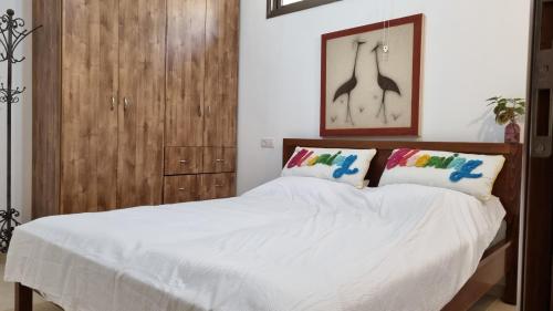 1 dormitorio con 1 cama blanca y armario de madera en שני חדרי שינה, חניה חינם, איזור שקט ויוקרתי,, en Rechovot