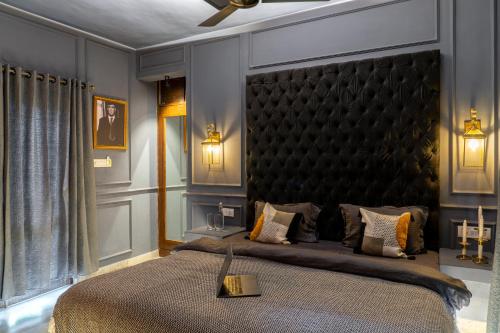 a bedroom with a large bed with a black headboard at Whoopers Boutique Hotel, Anjuna in Anjuna