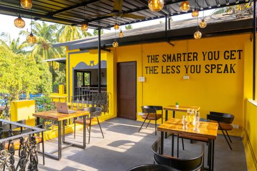 a restaurant with tables and chairs and a yellow wall at Whoopers Boutique Hotel, Anjuna in Anjuna