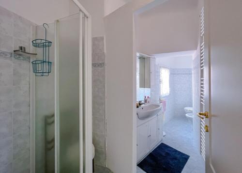 a white bathroom with a sink and a shower at Splendido appartamento con vista mare su piazza Dante in Varazze