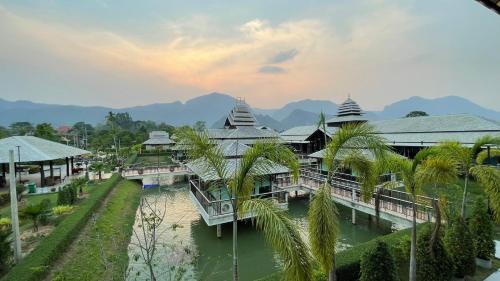 un complejo con un río, edificios y palmeras en Vathanagul Resort en Chiang Rai