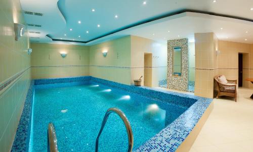 a large swimming pool in a room with a tub at Chaika Gostinichny Kompleks in Karagandy