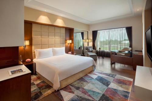 una camera con un grande letto bianco e un soggiorno di Taj Hotel & Convention Centre, Agra ad Agra
