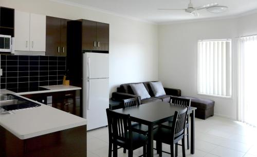 Monterey Apartments Moranbah في مورانبا: مطبخ وغرفة معيشة مع طاولة وكراسي