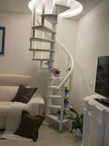 una scala a chiocciola bianca in un soggiorno con divano di Casa Vacanze “Il Sogno” a Bagnoregio